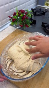 Folding the edges of the sticky bread dough towards the center with oiled fingers.