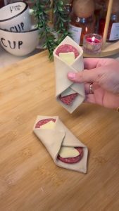 Folding the edges of the pastry to seal the cheese and sausage inside.