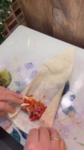 Folding the sides of the yufka triangle to seal the cheese inside.