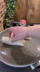 Frying the yufka rolls in a pan with hot oil until they turn golden.