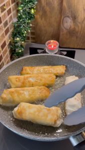 Draining freshly fried golden pizza böreks on a paper towel.