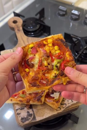 A baking tray filled with golden brown puff pastry mini pizzas topped with sucuk and cheese.