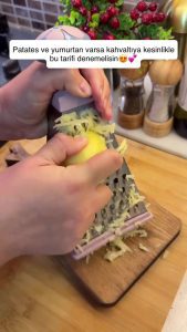 Grating medium-sized peeled potatoes using a box grater into a bowl.