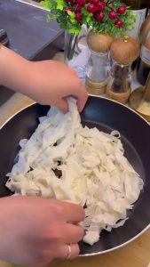 Greasing a non-stick frying pan with butter to prevent the borek from sticking.