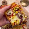 A large tray of freshly baked homemade Turkish pizza with sucuk, peppers, and melted kashar cheese.