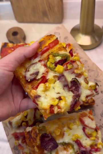 A large tray of freshly baked homemade Turkish pizza with sucuk, peppers, and melted kashar cheese.