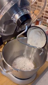 Kneading a soft and slightly tacky homemade pizza dough in a glass bowl.