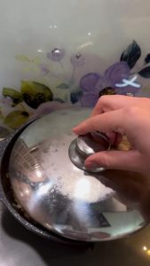 Covering the frying pan with a lid to melt the cheese perfectly over the eggs.