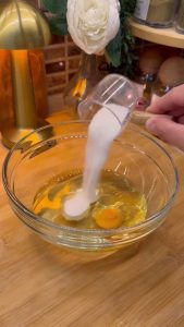 Mixing egg, vegetable oil, and vinegar in a bowl for Turkish sesame cookies.