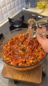 Combining rinsed rice, ground meat, tomato paste, and red pepper paste in a large mixing bowl.
