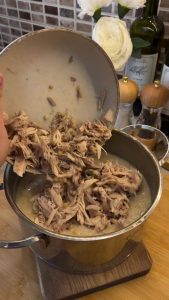 Mixing the shredded chicken back into the beaten wheat to reach the elastic Keşkek consistency.