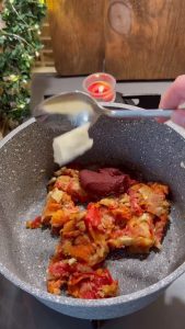 Stirring red pepper paste and butter into the sautéing soup base.