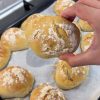 A basket of fresh, crusty no-knead spoon bread rolls with a flour-dusted top.
