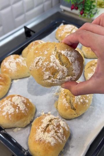 A basket of fresh, crusty no-knead spoon bread rolls with a flour-dusted top.