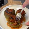 A dish of golden-brown Turkish stuffed peppers served with a side of sauce.