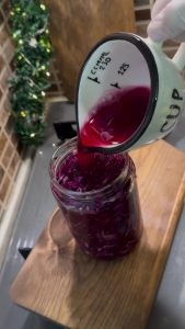 Packing the massaged red cabbage tightly into glass storage jars.