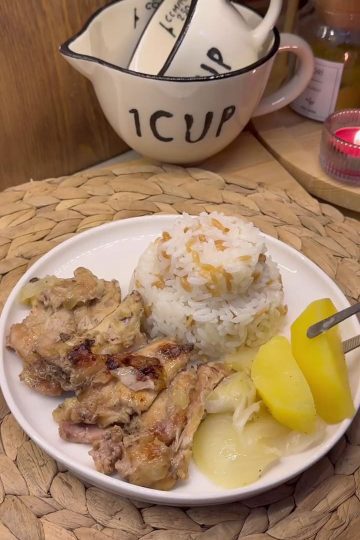 A tray of golden-brown pan-seared chicken butterfly pieces served with roasted potatoes and onions.
