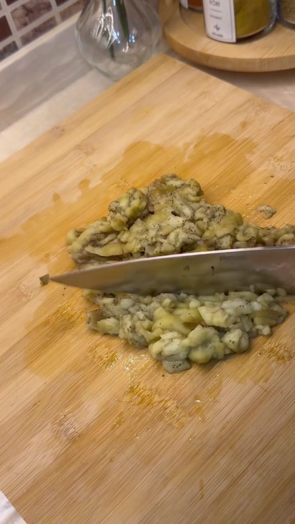 Peeling charred eggplant skins and mashing the soft flesh.