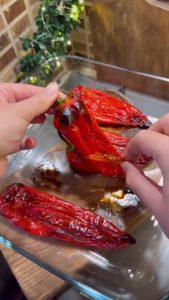 Peeling the skin off a roasted red pepper to reveal the soft flesh.