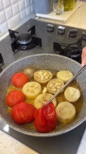 Removing the softened skins from the steamed tomatoes using a fork.