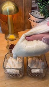 Piping the silky whipped milk pudding over the crumbled cake layer in a cup.