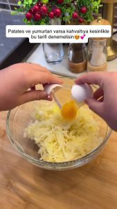 Transferring the dry, squeezed grated potatoes into a clean mixing bowl.