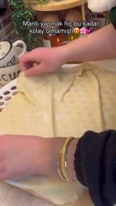 Laying a thin sheet of dough over a honeycomb mantı mold.