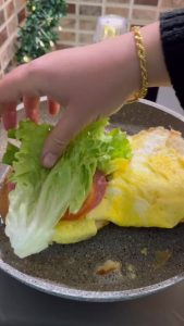 Adding sliced tomatoes and fresh lettuce to the one-pan egg sandwich.