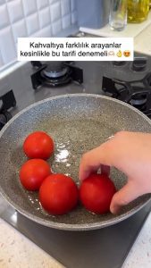Placing small trimmed tomatoes in a skillet with vegetable oil.