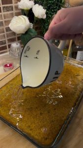 Pouring cold sugar syrup over the warm poppy seed semolina cake.