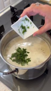 Adding a carton of liquid heavy cream to the thickened mushroom soup in the pot.
