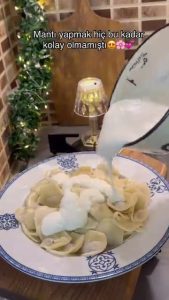 Pouring sizzling red pepper and mint butter sauce over Turkish dumplings.
