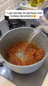 Pouring hot water over the sautéed vermicelli and simmer over medium heat.