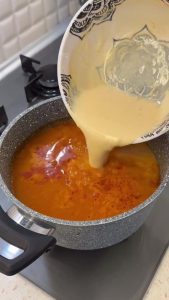 Slowly whisking the tempered yogurt-egg mixture back into the vermicelli soup pot.