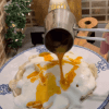 A plate of Turkish mantı dumplings topped with white garlic yogurt and red spicy butter sauce.