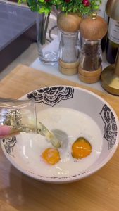 Whisking eggs, milk, and vegetable oil in a mixing bowl for the borek sauce.