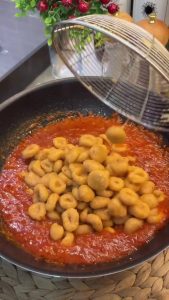 Sautéing minced garlic, grated tomatoes, and red pepper paste in a pan for the sauce.