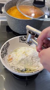 Whisking yogurt, egg, flour, and minced garlic in a separate bowl for seasoning.