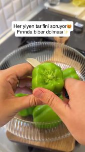 Cutting the tops off green bell peppers to create lids and removing the seeds for stuffing.
