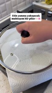 Covering the rice pan with a paper towel and lid for a 30-minute resting period.