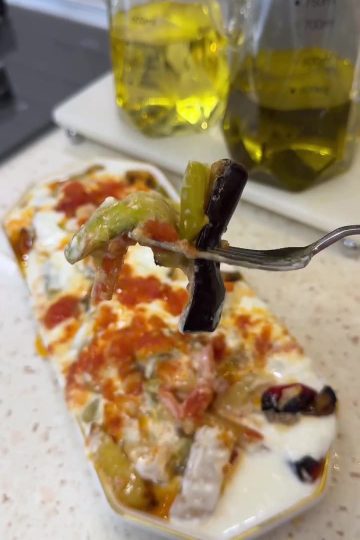 A platter of oven-roasted Mediterranean vegetables topped with tomato sauce and yogurt.