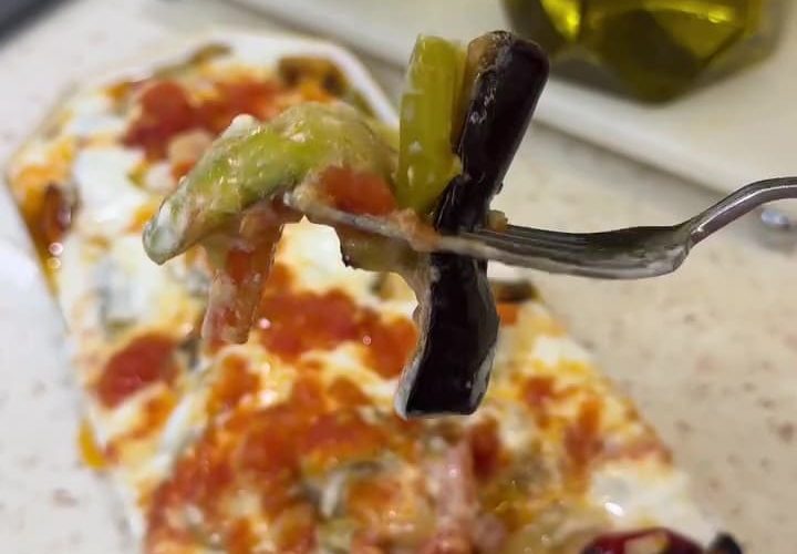 A platter of oven-roasted Mediterranean vegetables topped with tomato sauce and yogurt.