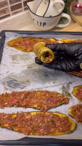 Rolling the roasted eggplant strip around the ground meat filling.