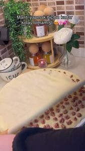 Using a rolling pin to seal and cut the dumplings on a mantı mold.