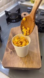 Sprinkling salt and red paprika over the buttery corn kernels for extra flavor.