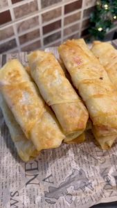 Serving hot Turkish pizza böreks with melting cheese and savory sucuk.