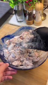 Shaking the flour-coated chicken livers to remove excess flour before frying.