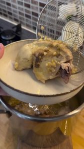 Shredding the cooked chicken thighs into thin pieces using two forks.