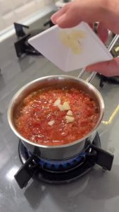 Cooking grated tomatoes and garlic in a small saucepan for the topping.