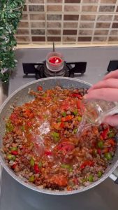 Adding tomato paste, grated tomatoes, and water to the meat filling to simmer.